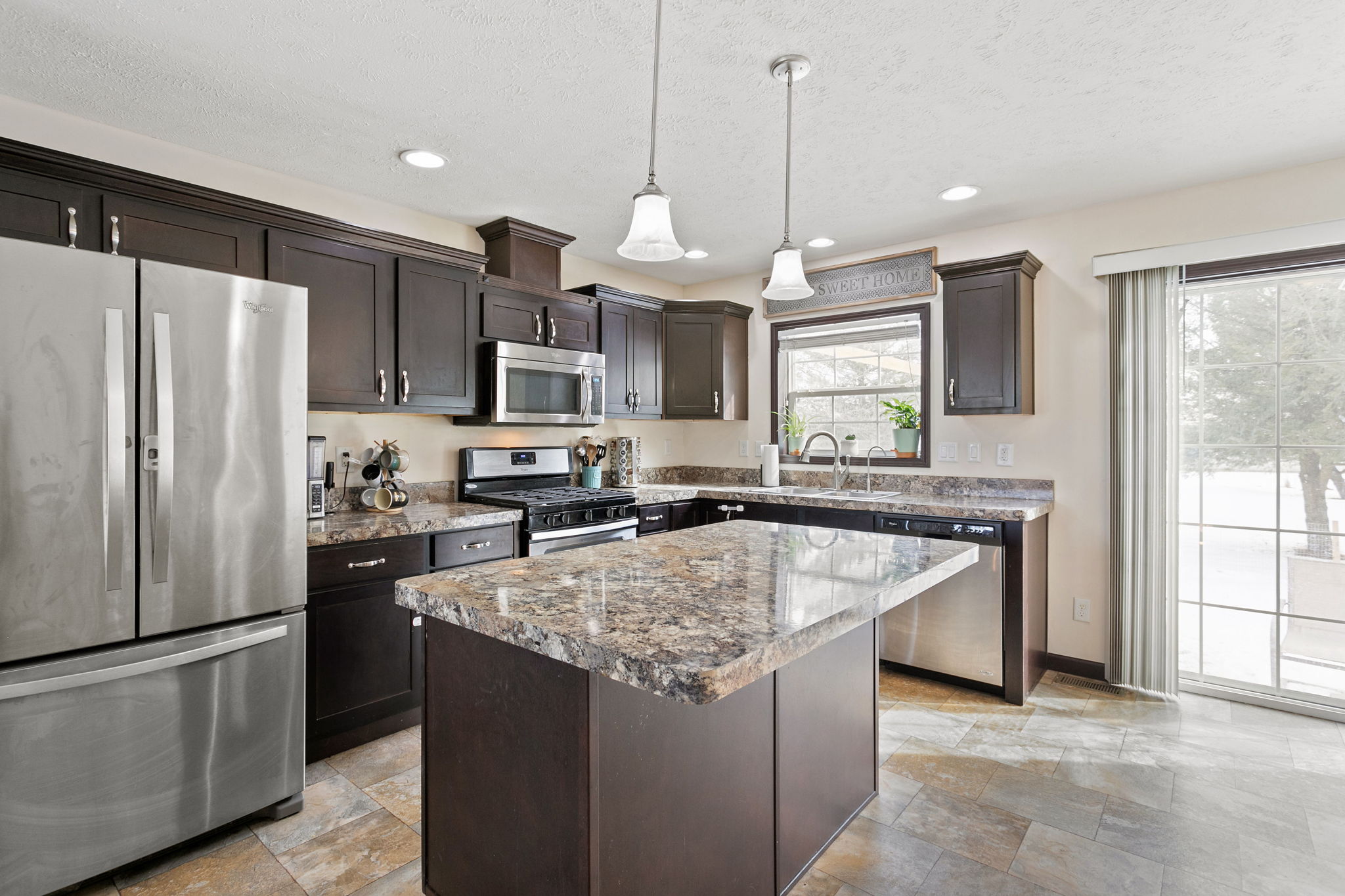 Bright kitchen with a center island, window over the sink, and sliding glass door leading outside.
