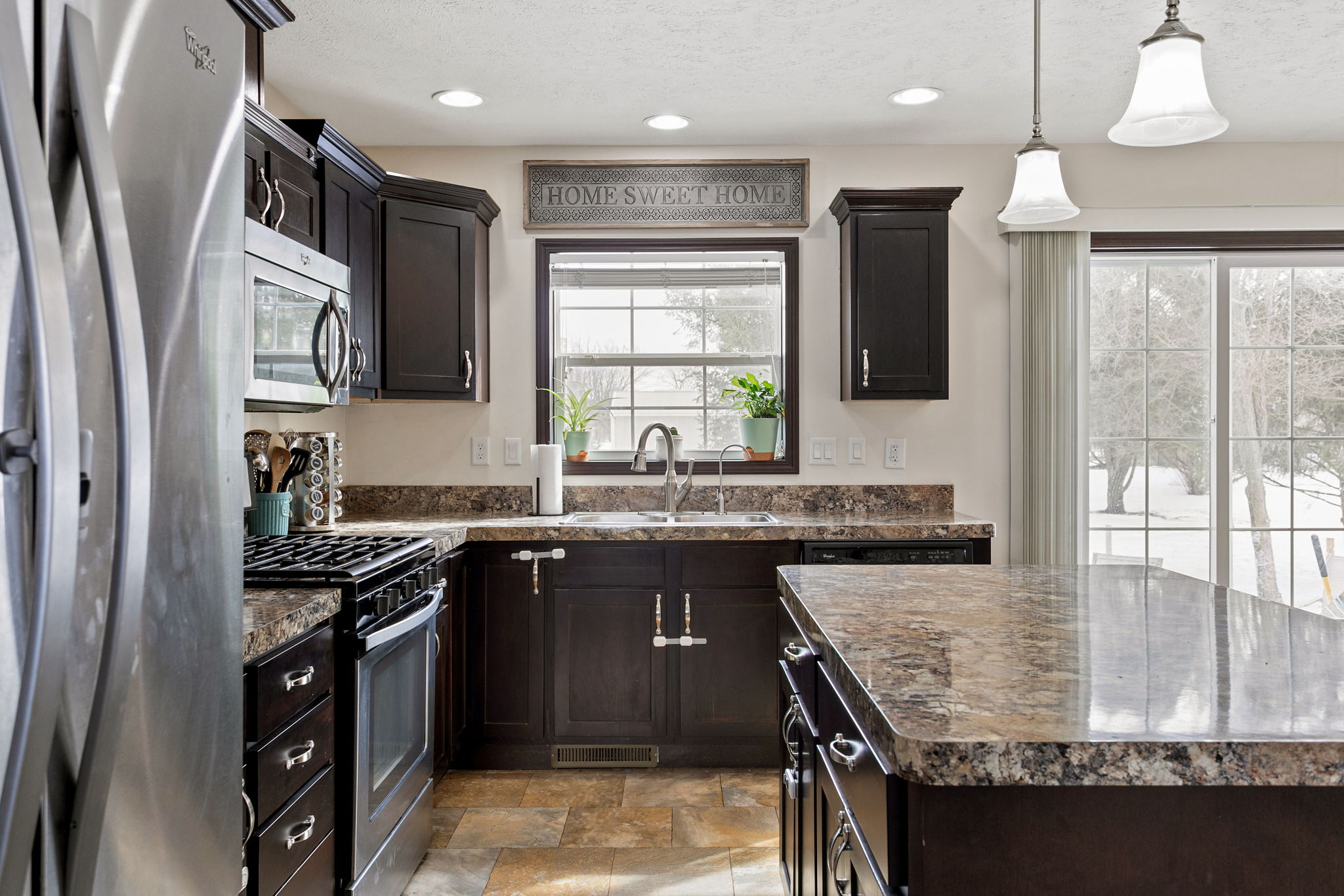 Close-up of kitchen window with dark cabinets, granite countertops, and double sink