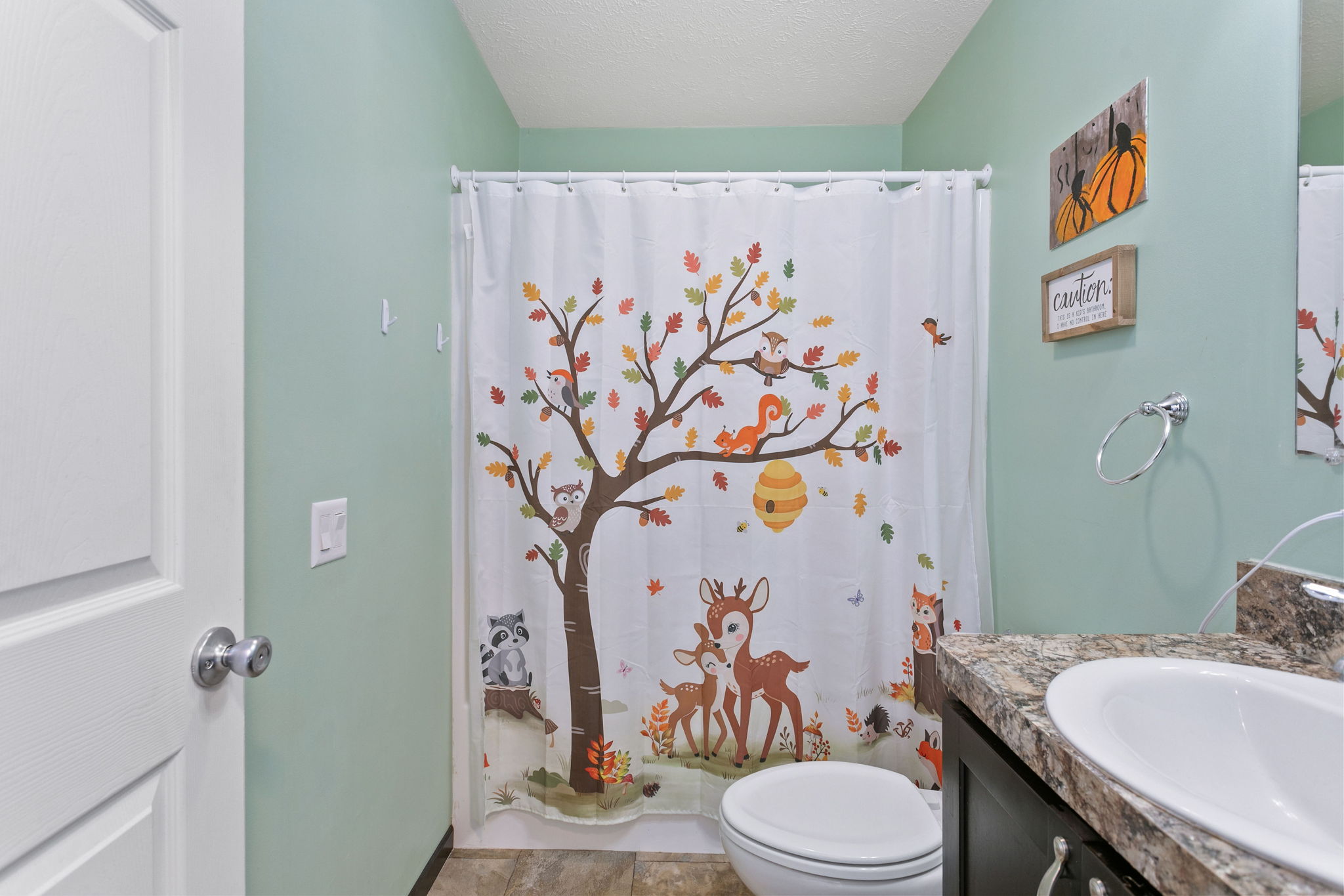 Guest bathroom with forest animal-themed shower curtain and mint green walls