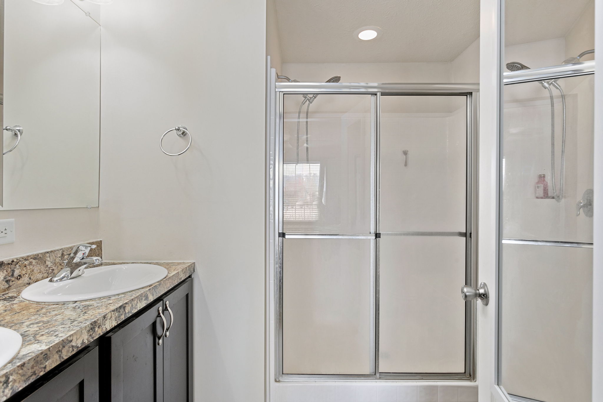 Primary bathroom with glass shower enclosure and granite vanity