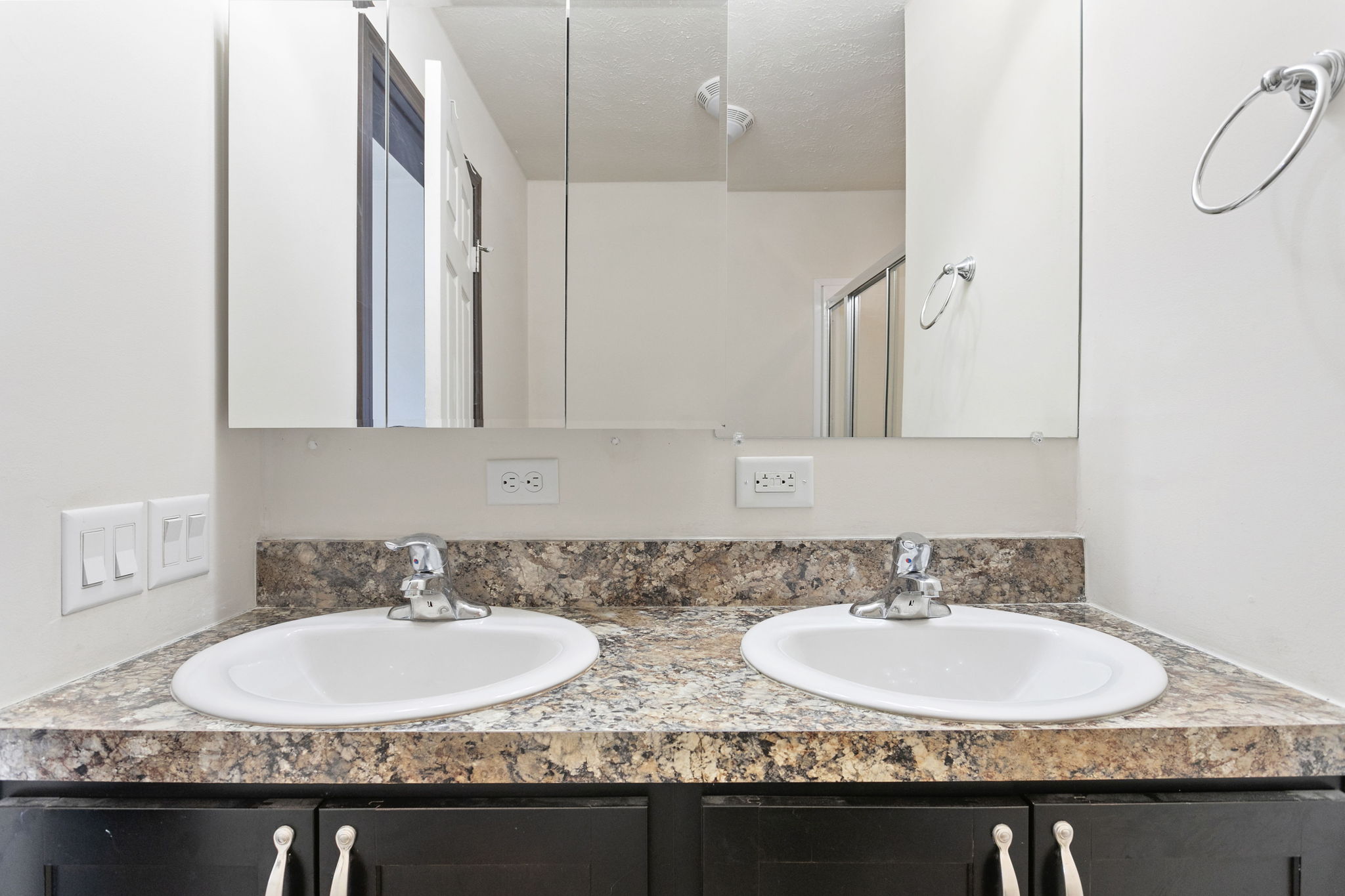 Double sinks in primary bathroom with large mirrors and granite countertops