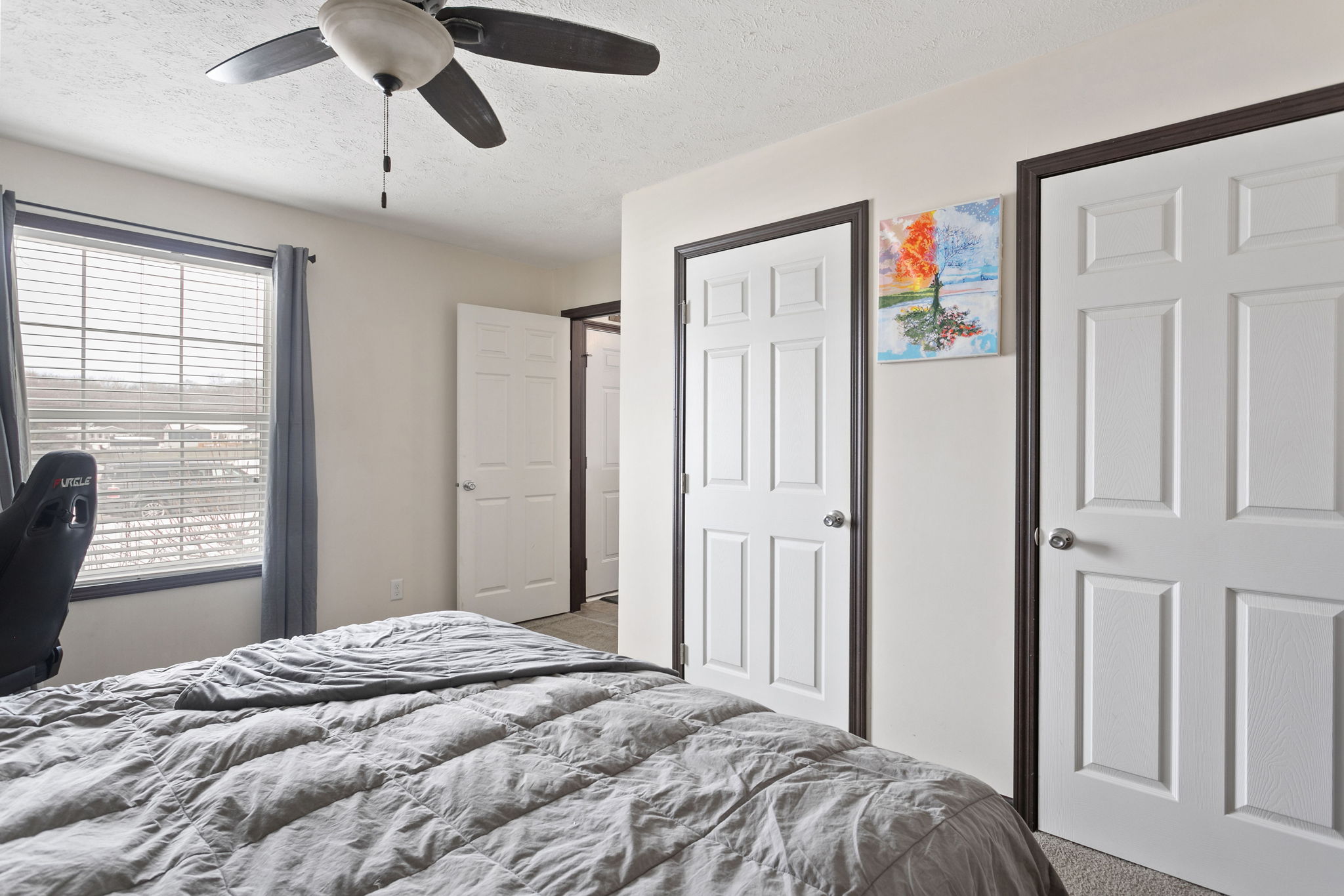 Bedroom with ceiling fan, two closets, and bright natural light from window