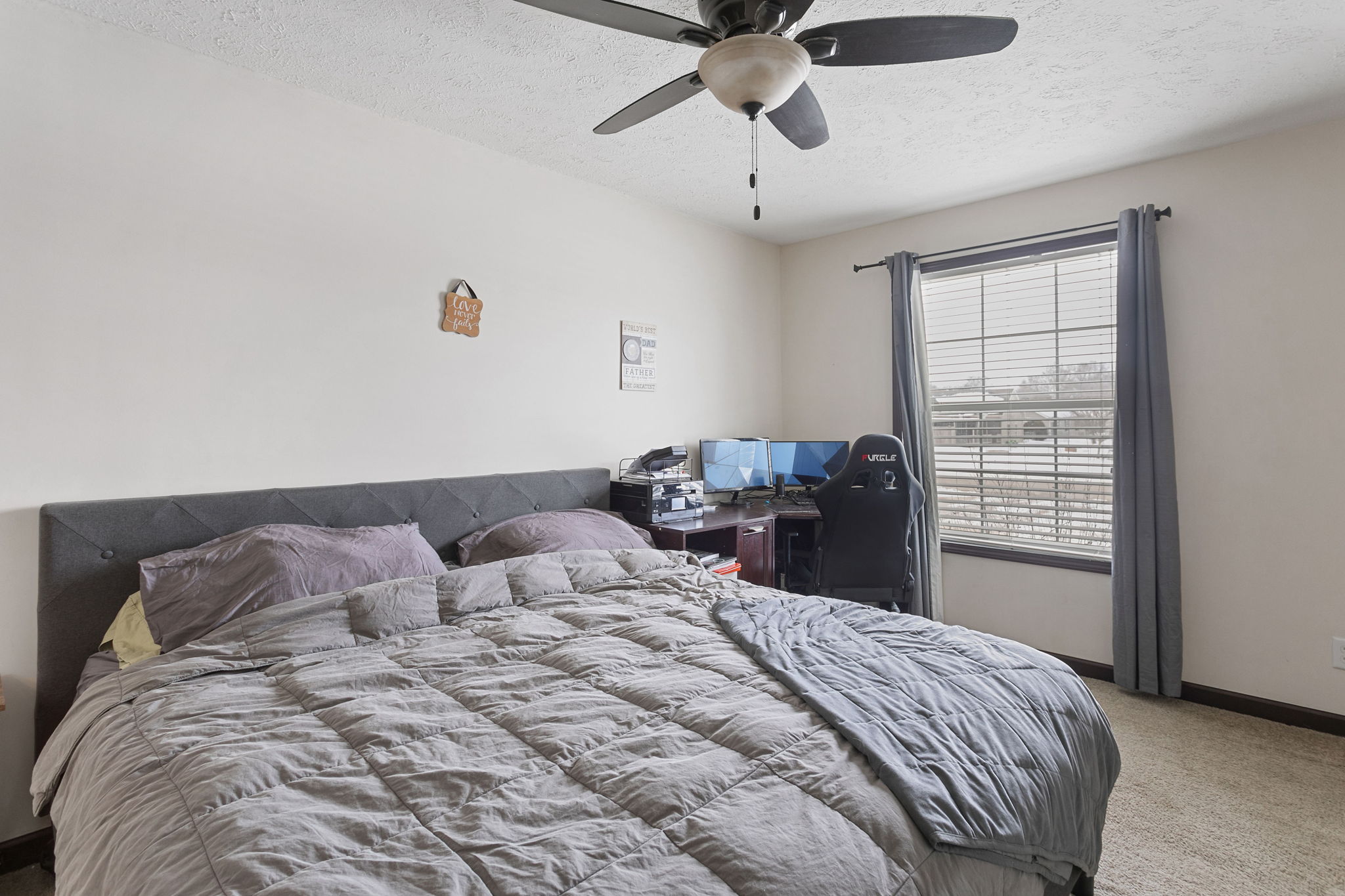 Primary bedroom with king-size bed, home office desk, and dual windows