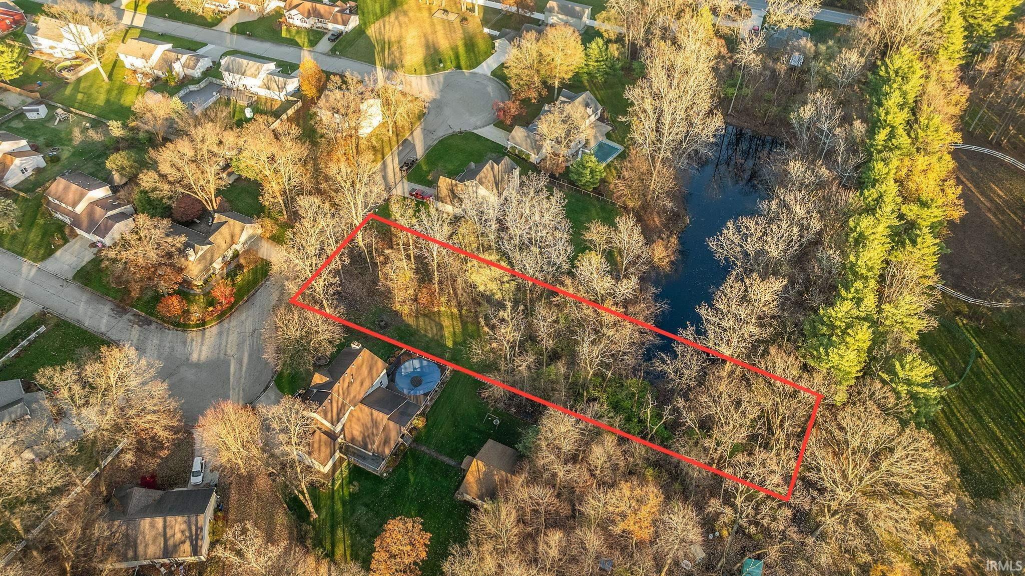Tree-lined residential lot with pond access outlined in red in Mishawaka, IN.