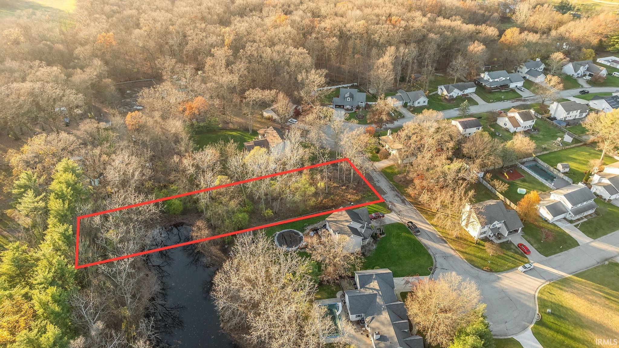 Angled aerial view of wooded lot near cul-de-sac and pond in Mishawaka, IN subdivision.