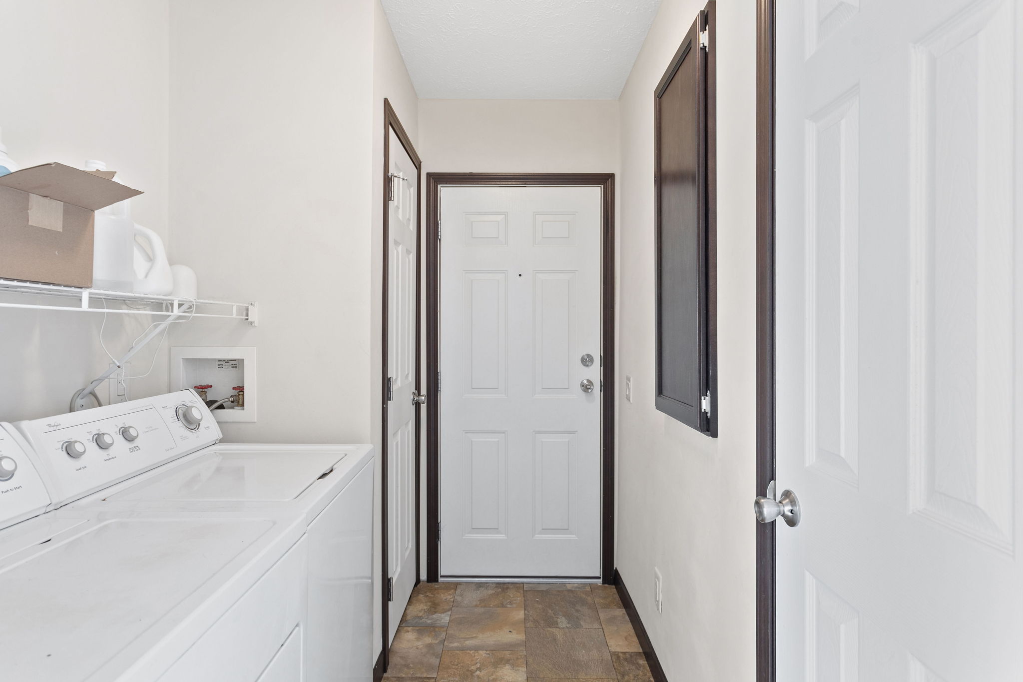 Laundry room with washer and dryer, shelf storage, tile floor, and door access to the garage.