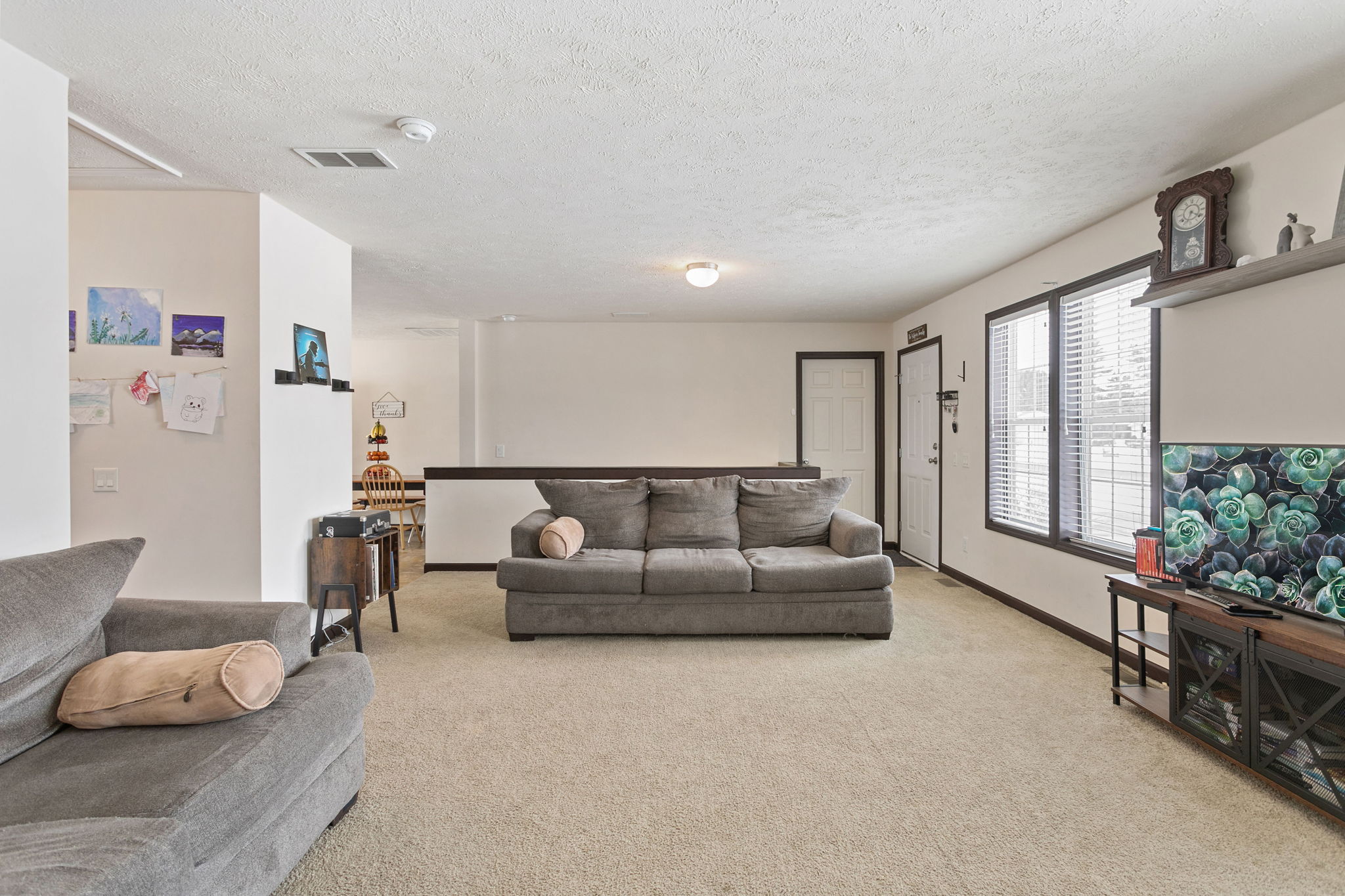 Spacious living area with multiple couches, large windows, and an open layout leading to the dining space.