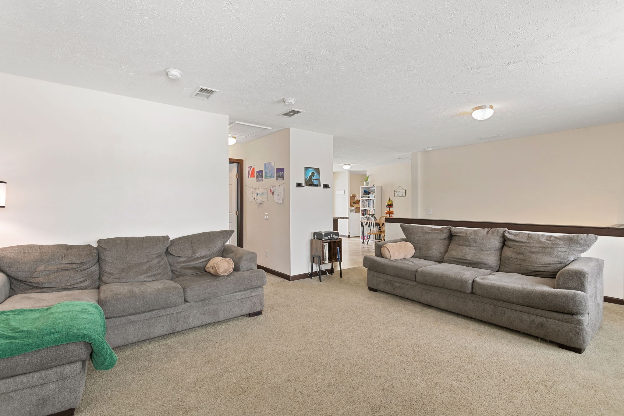 Alternate view of the living room showcasing both seating areas and access to the dining and kitchen.