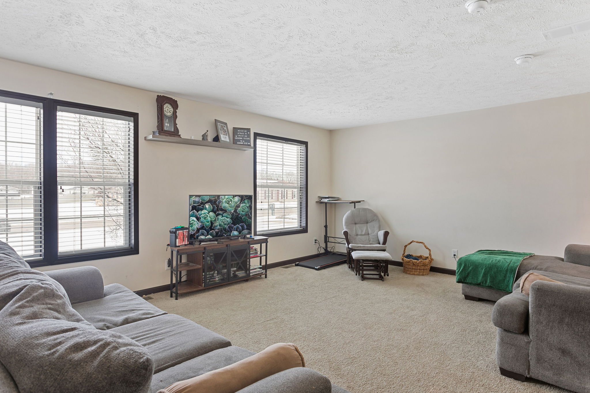 Cozy family room with large windows, a TV, and a glider chair in the corner.