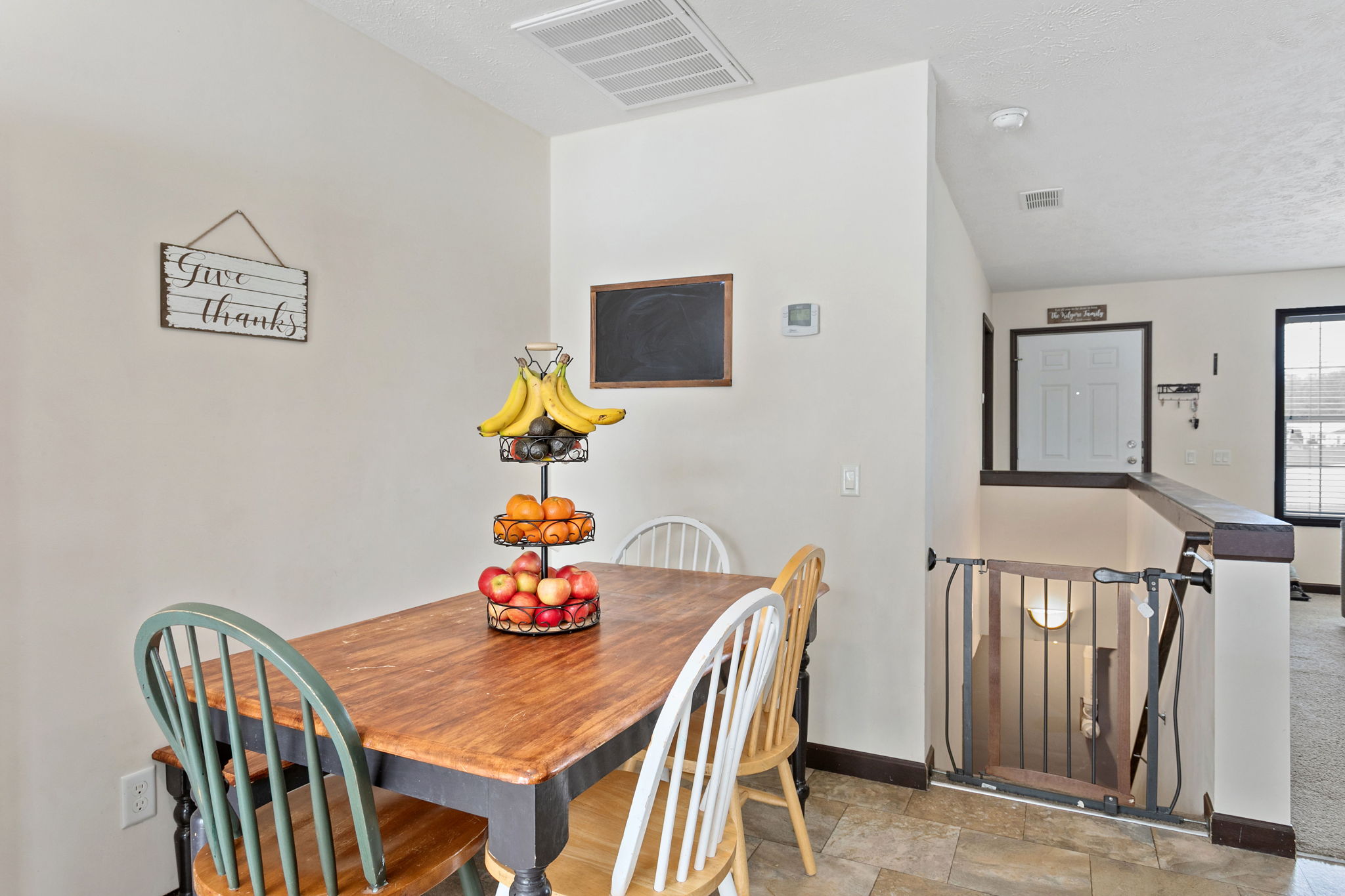 Small dining nook with a wooden table and mismatched chairs, situated near the stairs.