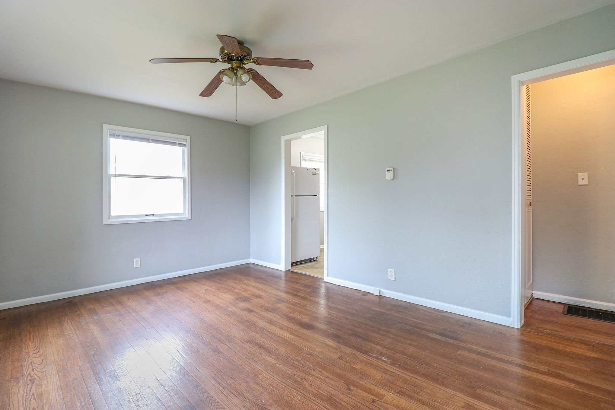 Living room with hardwood floors, gray walls, and ceiling fan in South Bend home.