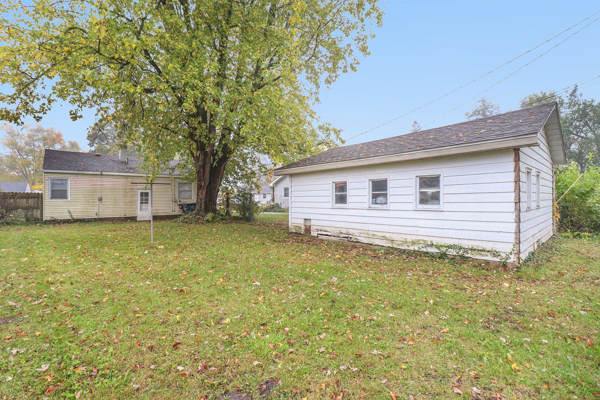 Backyard with mature tree, grassy lawn, and detached white garage with multiple windows