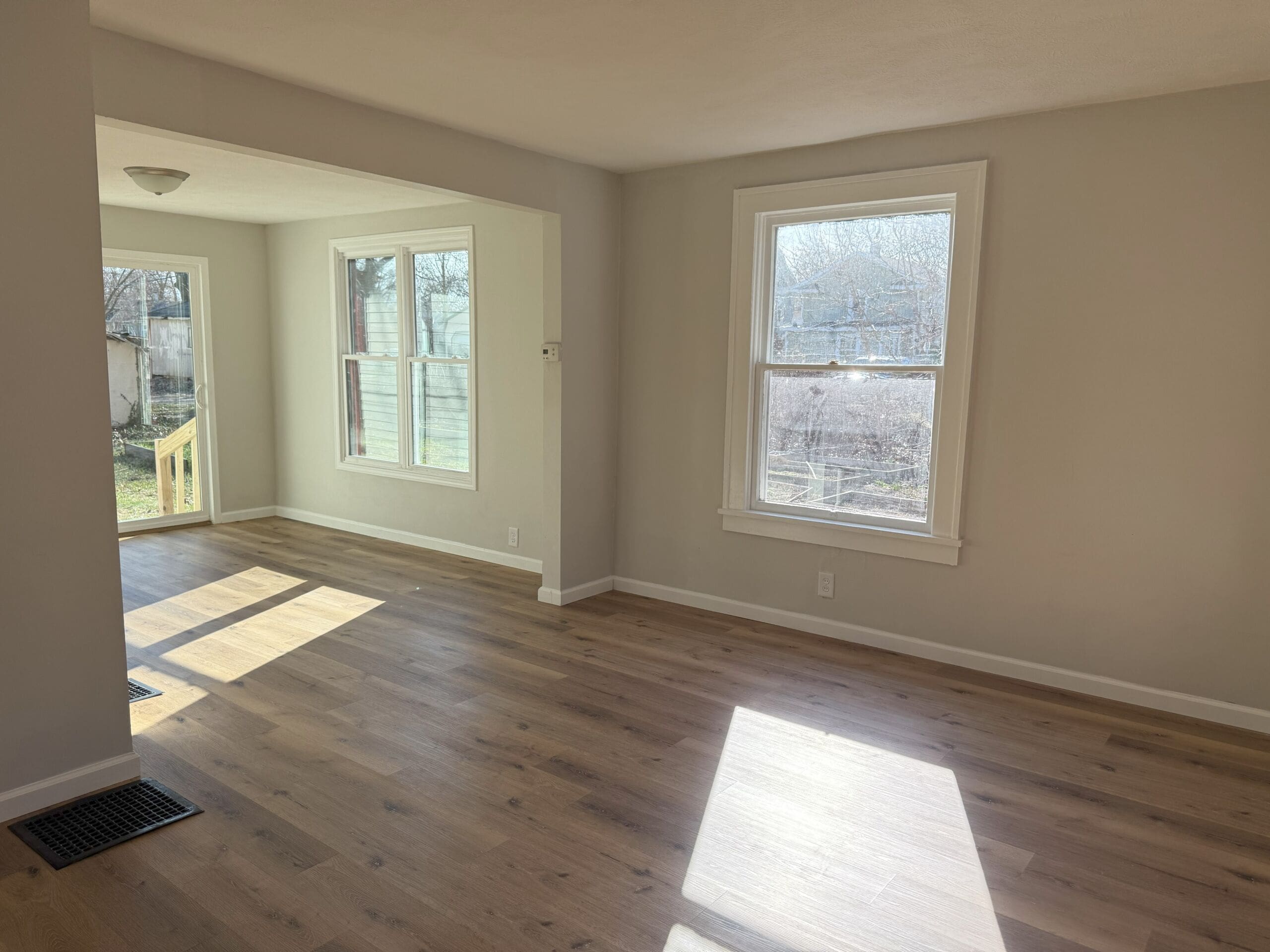 Bright open-concept living and dining area with large windows and wood flooring